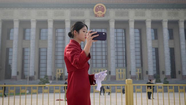 An attendant takes a selfie outside the Great Hall of the People in Beijing on Tuesday. Picture: AFP