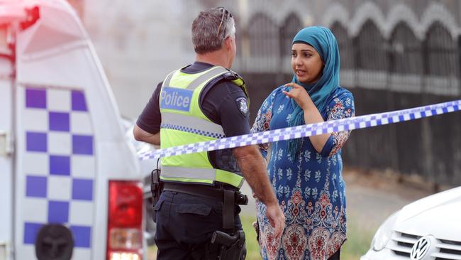 A police officer speaks with a woman after the shootings. Picture: Andrew Henshaw