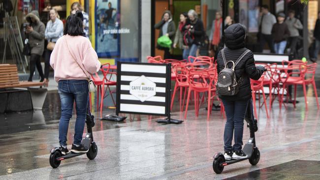 People without helmets riding scooters down Rundle Mall. Picture: Simon Cross