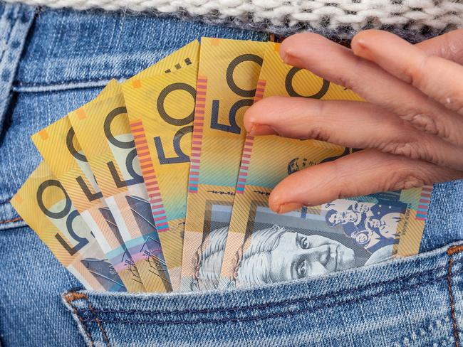 Female hand reaching for 50 Australian dollar bills in her jeans back pocket