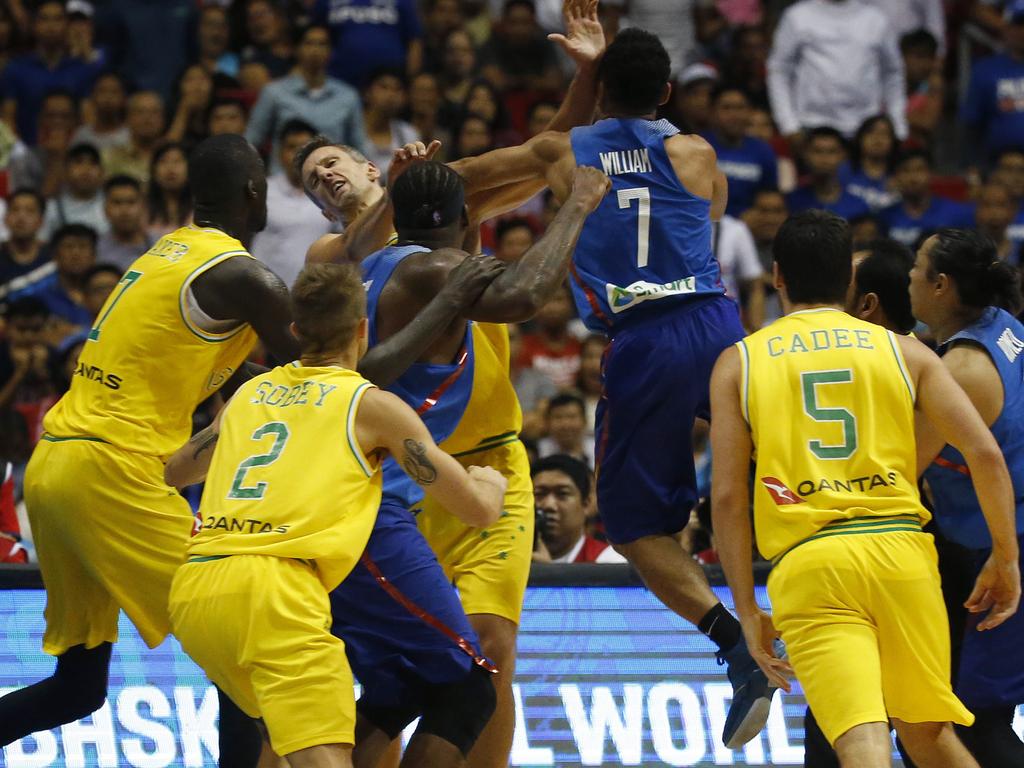 The Philippines' Jason William, centre, jumps to hit Australia's Daniel Kickert centre left as others rush to break the brawl during the FIBA World Cup Qualifiers Monday, July 2, 2018 at the Philippine Arena in suburban Bocaue township, Bulacan province north of Manila, Philippines. Australia defeated the Philippines 89-53 via default following a brawl in the third quarter. (AP Photo/Bullit Marquez)