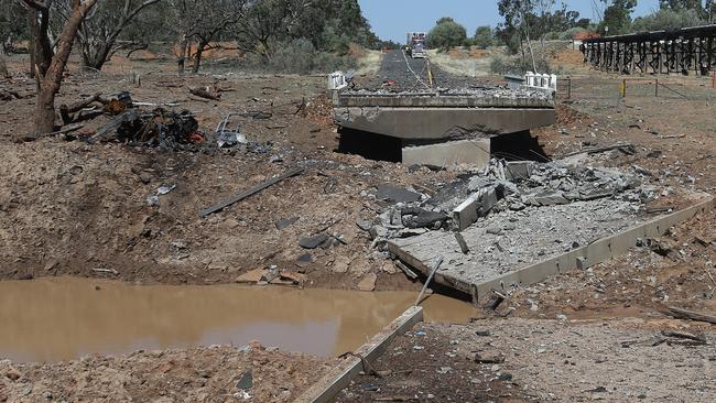 The remains of the truck (left) beside the road crater.