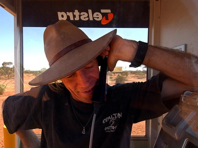 Opal miner Colin Duff makes a phone call from a solar powered Telstra telephone box in the Queensland outback town of Opalton, Sunday, Sept. 25, 2005. Legislation was passed earlier this month to pave the way for the sale of the government's 51.8% remaining share holding in Telstra. Some farmers groups have expressed concerns about the adequacy of the government's promised $3.1 billion in sweeteners to improve telecommunications services in the bush. (AAP Image/Mick Tsikas) NO ARCHIVING