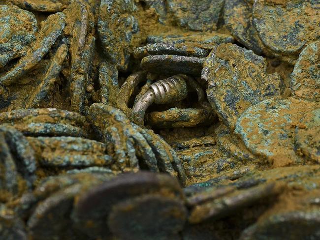 Tantalising traces ... A piece of jewellery peeks between some of the 70,000 coins of the Jersey hoard. Source: Jersey Heritage