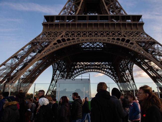 (FILES) In this file photo taken on November 2, 2018 people walk along the Eiffel tower in Paris. - The Eiffel Tower will be closed on December 8, 2018 amid 'yellow vest' protests planned on the same day in Paris. (Photo by STRINGER / AFP)