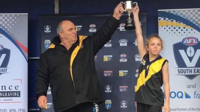 Seaford junior footy coach Mal Lehner and daughter Dakota hold up the premiership cup in 2017.