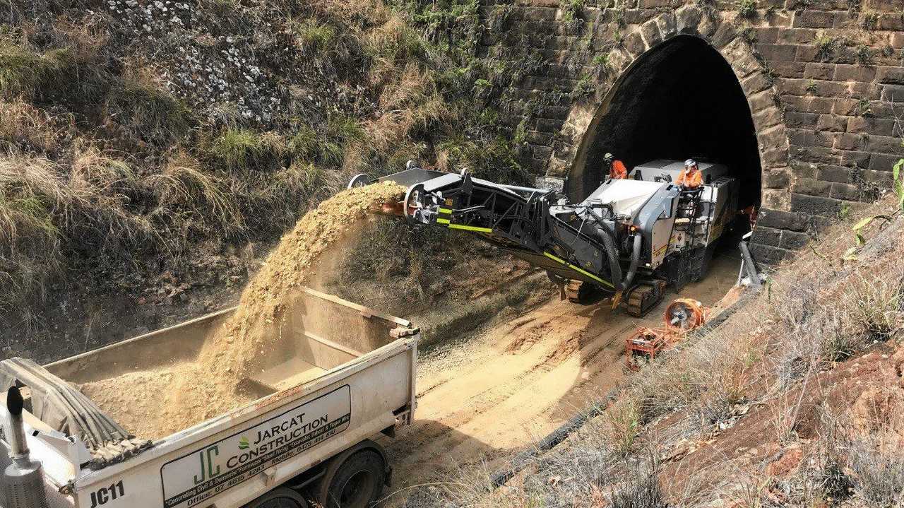 Workers dredging gravel and sand to lower and widen an old train tunnel along the range to make them large enough to handle modern contain freight. Picture: TMR