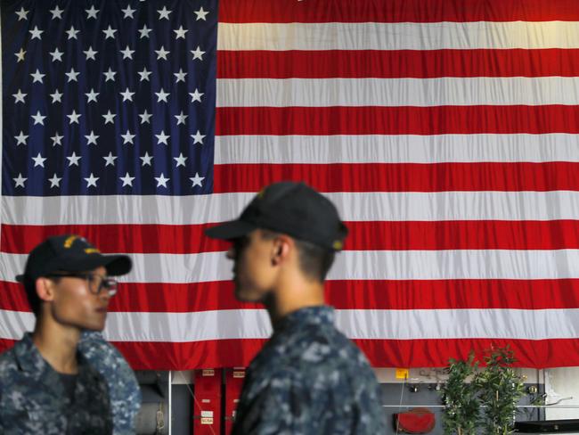 US Navy servicemen stand in front of an American national flag at the USS Ronald Reagan aircraft carrier in Hong Kong earlier this month. Picture: AP /Vincent Yu