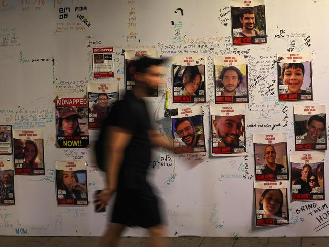 A man walks past portraits of Israeli hostages posted on a wall in Tel Aviv. Picture: AFP