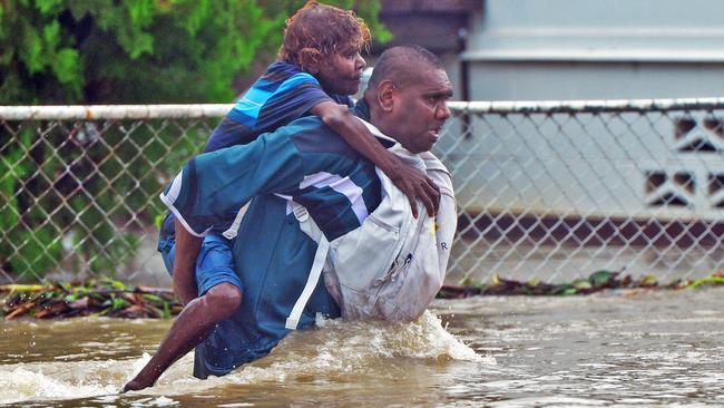 Leslie Noble carries his aunty Clara Fullerton across floodwaters on the corner of Norris Street and Queens Road. Picture: Zak Simmonds