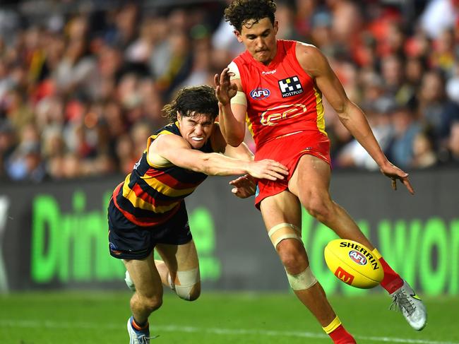 GOLD COAST, AUSTRALIA - JUNE 19: Wil Powell of the Suns is tackled while kicking the ball during the round 14 AFL match between the Gold Coast Suns and the Adelaide Crows at Metricon Stadium on June 19, 2022 in Gold Coast, Australia. (Photo by Albert Perez/Getty Images)