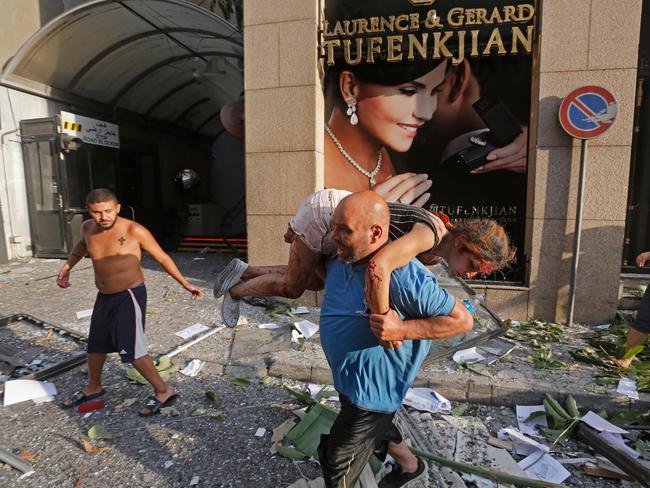 A man carries away an injured girl while walking through debris in the Achrafiyeh district in the centre of Lebanon’s capital Beirut on August 4, 2020. Picture: Marwan Tahtah/AFP