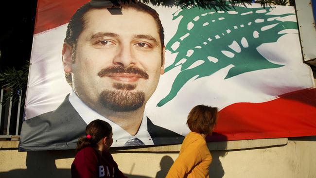 A woman and her daughter pass by a poster of outgoing Prime Minister Saad Hariri, in Beirut, Lebanon. Picture: AP