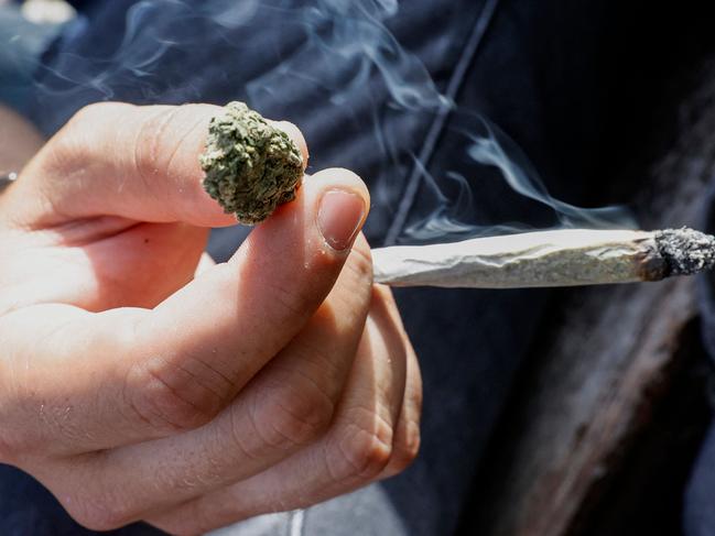 A man holds a joint and a cannabis bud in his hand as people gather in Rabin Square in the Israeli coastal city of Tel Aviv on April 20, 2021 to mark "World Cannabis Day" (4/20), smoking different forms of cannabis. - World Cannabis Day is celebrated in many countries on April 20 by participants from a wide variety of backgrounds, particularly around twenty minutes past 4 pm. (Photo by JACK GUEZ / AFP)