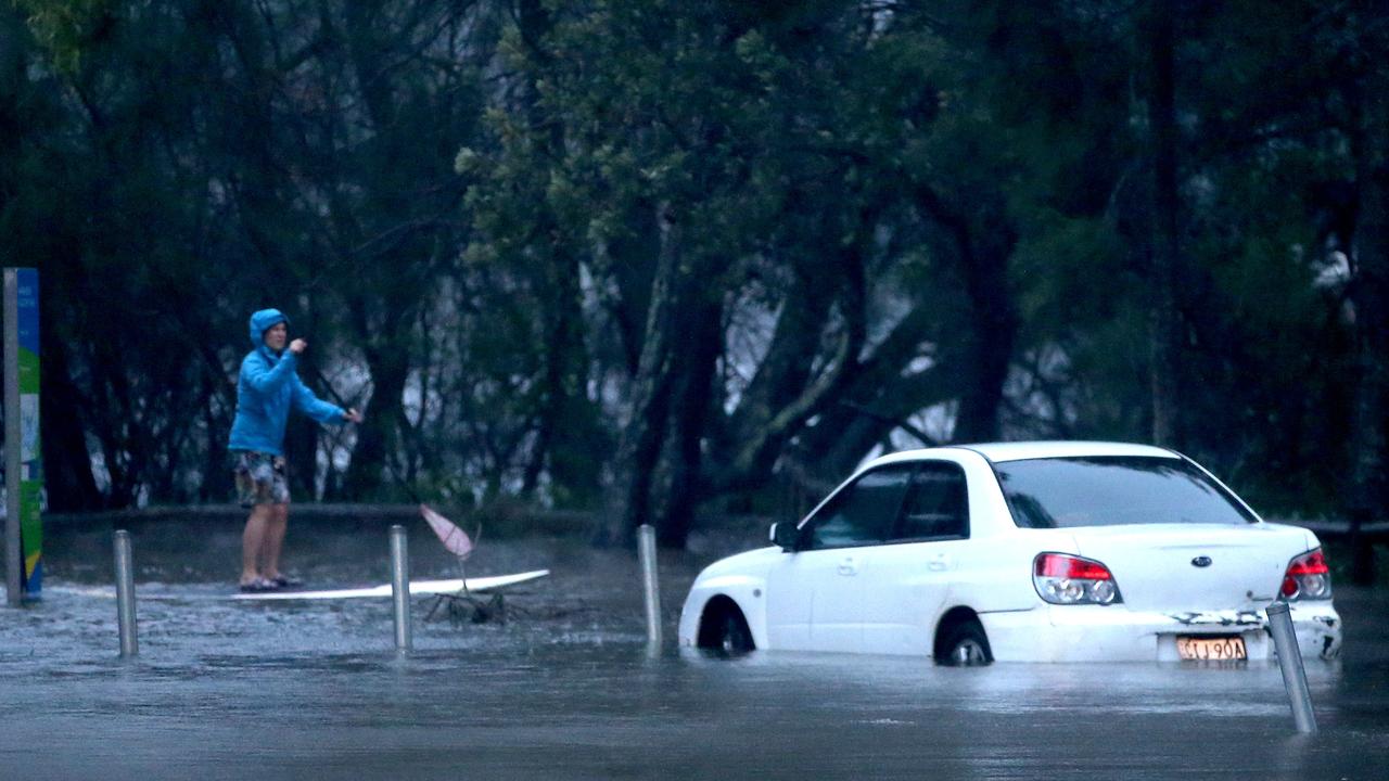 A person on a paddle board on a flooded Goodwin Street Narrabeen near Narrabeen lagoon. Picture: Damian Shaw