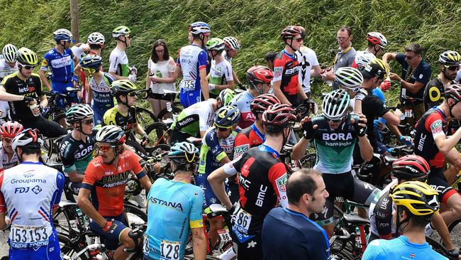 The pack of riders waits for the stage to resume, after tear gas was used during a farmers' protest who attempted to block the stage's route, during the 16th stage of the 105th edition of the Tour de France cycling race, between Carcassonne and Bagneres-de-Luchon, southwestern France, on July 24, 2018.  The race was halted for several minutes on July 24 after tear gas was used as protesting farmers attempted to block the route. / AFP PHOTO / Jeff PACHOUD