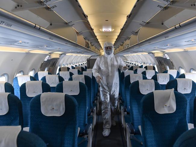 A worker wearing a protective suit disinfects a passenger plane ... a little under eight weeks until the start of the Dry, the NT tourism industry is worried about the impact the coronavirus crisis will have on an industry already on its knees. Picture: Nhac Nguyen/ AFP