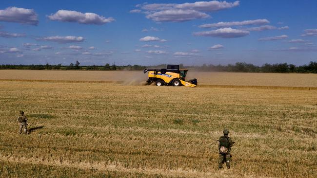 Russians stand guard as farmers harvest wheat near Melitopol, Zaporizhzhia region, on July 14. Picture: AFP