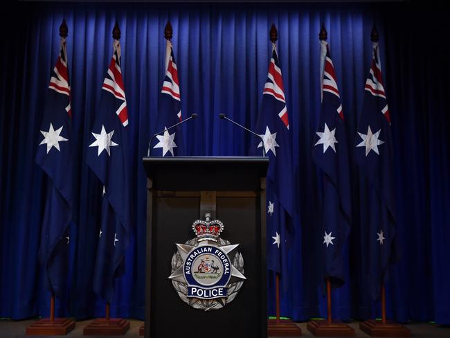 A lectern with the insignia of the Australian Federal Police stands vacant in front of six Australian flags after Prime Minister Tony Abbott gives a national security address at Parliament House in Canberra, Monday, Feb. 23, 2015. (AAP Image/Lukas Coch) NO ARCHIVING