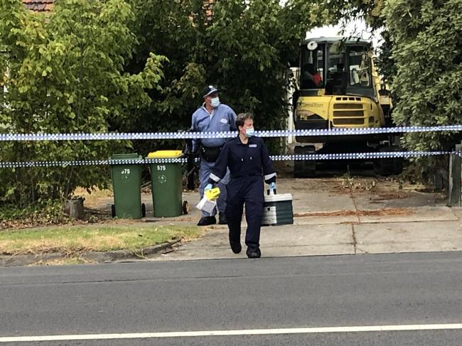 Forensic police emerge from the house with what appears to be a tissue box. Picture: James Mottershead