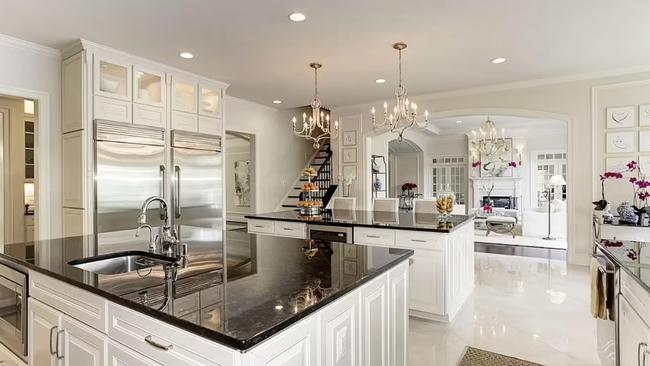 The kitchen features marble benchtops and chandeliers.