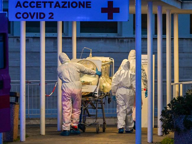 Medical workers in overalls stretch a patient under intensive care into the newly built Columbus Covid 2 temporary hospital in Rome. Picture: Andreas Solaro/AFP