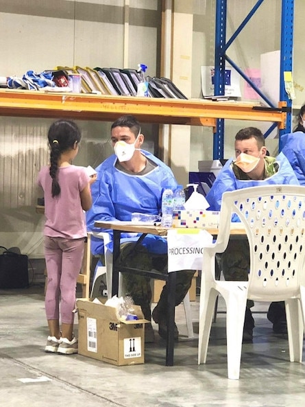 A little girl safely over the border with help from the Lancers plays chatterbox with officials at a processing centre in the UAE