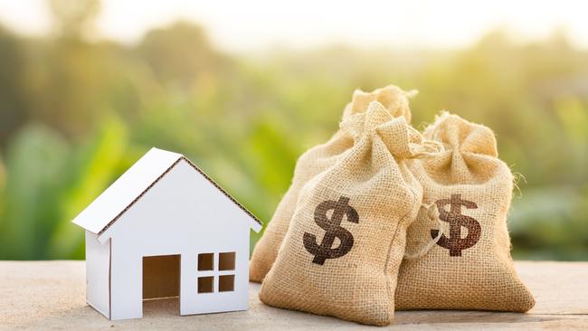 Loan and House concept. Money bags put near house on woodle desk at sunset and green nature background