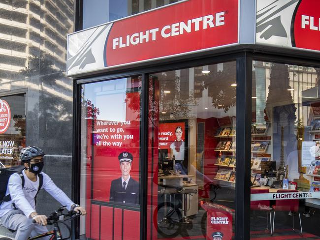 A cyclist rides past a Flight Centre store wearing a mask to protect themselves from Covid-19, Brisbane, Friday, May 1, 2020. (AAP Image/Glenn Hunt) NO ARCHIVING
