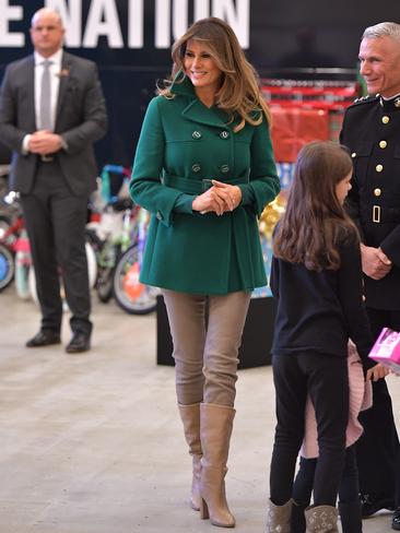 DECEMBER 13: A festive emerald green Prada coat, jeans and boots proved a stylish but practical combination as Melania helped with the Marine Corps Reserve Toys for Tots Campaign at Joint Base Anacostia-Bolling in Washington. The First Lady helped sort donated toys and decorated holiday cards with the children of military families. Picture: AFP