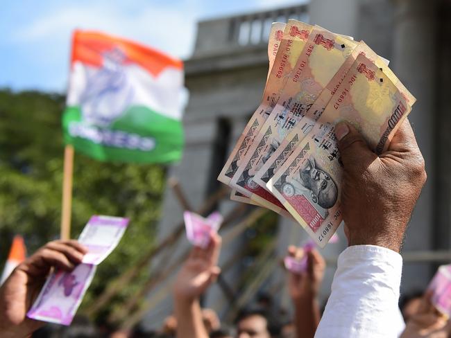 Indian supporters of the Congress Party hold Indian currency notes during a protest against the decision to demonitise 500 and 1000INR notes in Bangalore on November 28, 2016. Tens of thousands of people turned out November 28 for nationwide protests against India's controversial ban on high-value banknotes, which opposition party organisers say has caused a "financial emergency". / AFP PHOTO / Kiran MANJUNATH