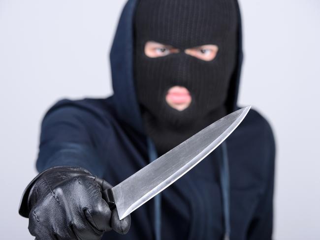 Masked man aims with knife. on gray background. Robbery, crime, knife generic