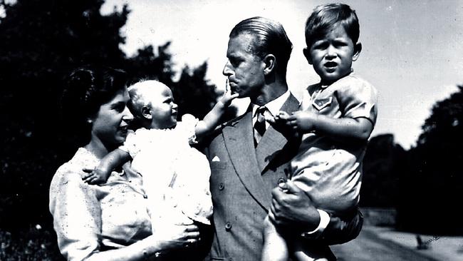 Queen Elizabeth II holding infant daughter Princess Anne and Prince Philip holding young son Prince Charles in the grounds of Clarence House.