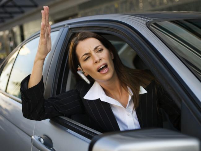 Businesswoman yelling out of car window. Road rage. Generic image.