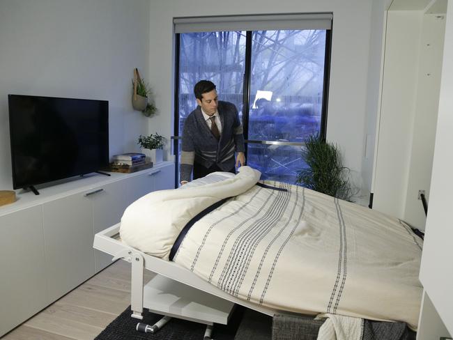 Christopher Bledsoe demonstrates a retractable bed that turns into a sofa when stored inside one of the apartment units. Picture: Julie Jacobson