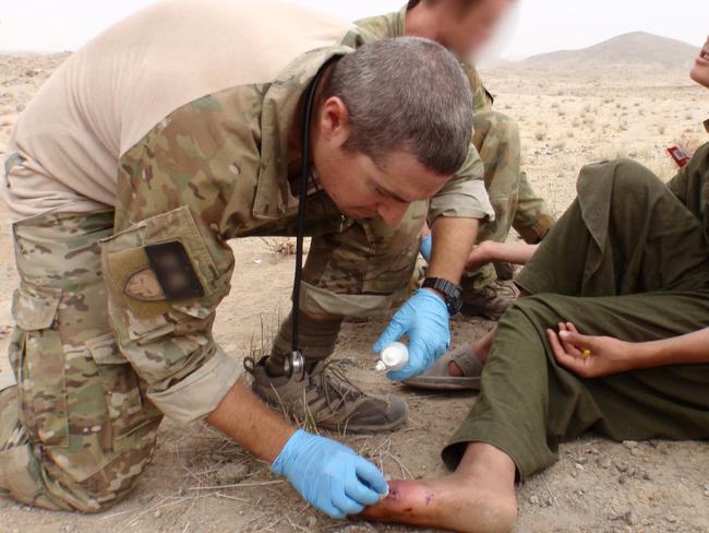 Corporal Tom Newkirk treats an injured boy. Picture: Supplied