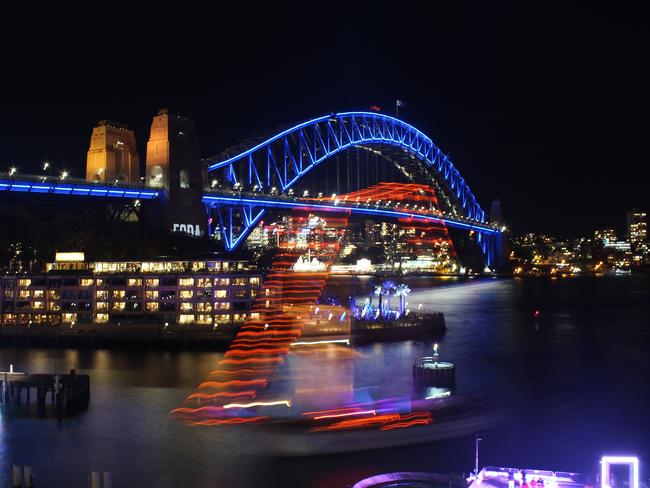 A slow shutter speed captures the light trail of a tall ship as it passes in front of Sydney Harbour Bridge during Vivid Sydney Festival. Picture: AAP.