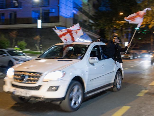 TBILISI, GEORGIA - OCTOBER 26: Georgian Dream Party supporters celebrate the exit poll results outside the new Georgian Dream headquarters during Georgian Election Day on October 26, 2024 in Tbilisi, Georgia. Georgians are voting on October 26, in a close parliamentary election that analysts say will likely determine whether or not the post-Soviet nation will take a step closer to membership in the European Union (EU). An opposition coalition is challenging the Georgian Dream ruling party, which has been in power since 2012 under the leadership of Bidzina Ivanishvili. The vast majority of Georgians are in favor of joining the EU, however the country's bid to become a member of the bloc was frozen earlier this year, following concerns over the "foreign agents" bill passed in May, which critics say represents a backslide for democracy. (Photo by Diego Fedele/Getty Images)