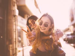 Hipster teenage girl on piggyback ride in the city doing the peace sign. Picture: iStock