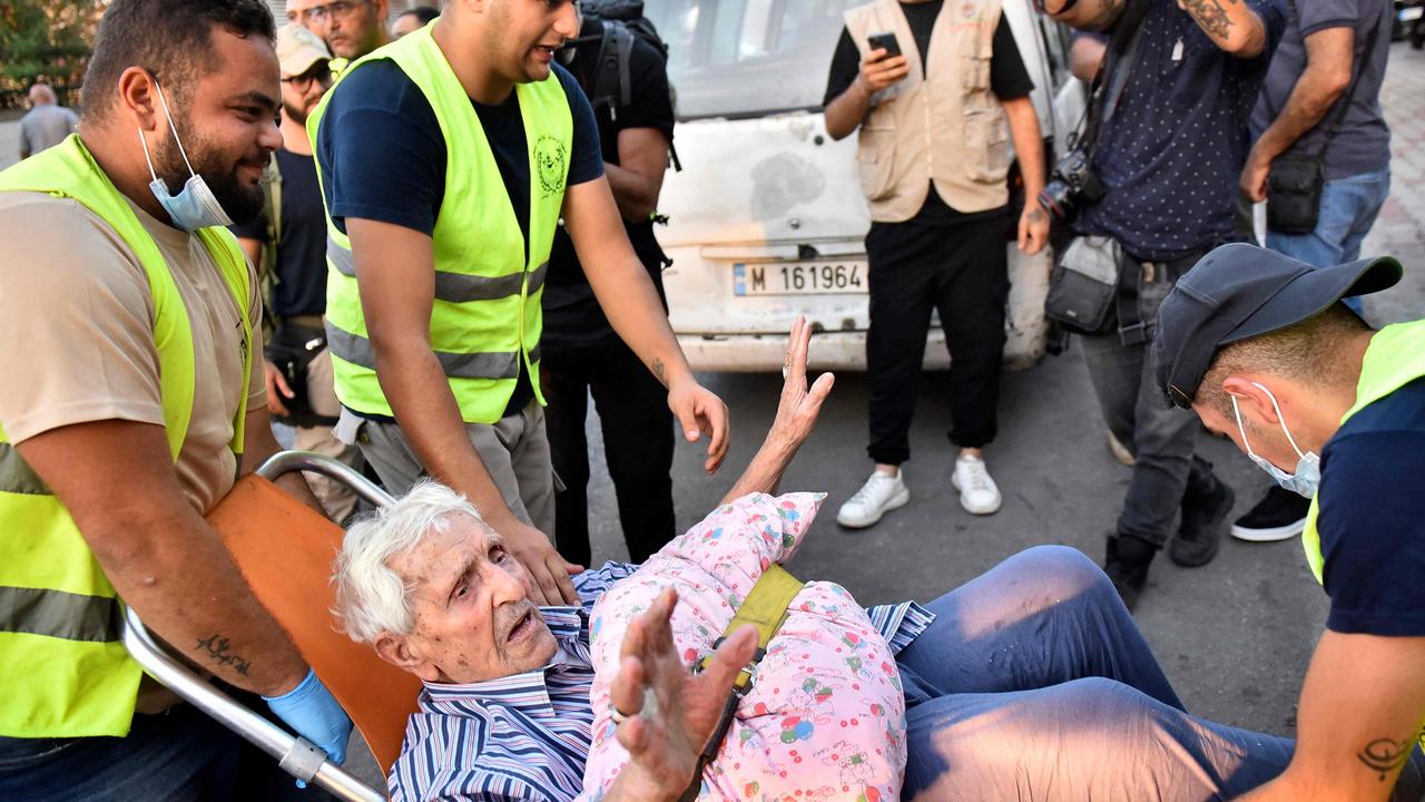 Volunteers carry an elderly man on a chair as people who fled their villages in southern Lebanon are received at an art institute transformed to a shelter for persons displaced by conflict. (Photo by FADED ITANI / AFP)