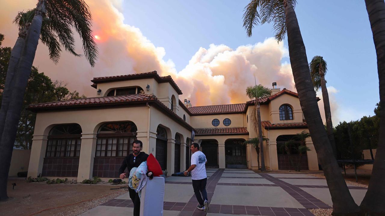 People evacuate their home as a brush fire burns in Pacific Palisafes, California. Picture: AFP