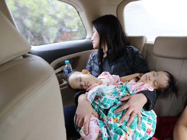 Travelling nurse Tshewang Choden holds Nima and Dawa in the car after arriving into Melbourne. Picture: Alex Coppel