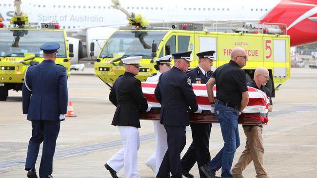 Draped in USA flags, the caskets of the killed fireys are carried to the aircraft.