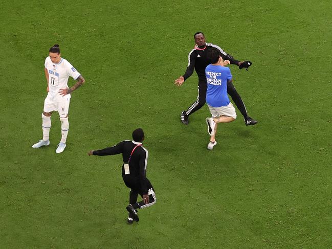 Security guards tackle the pitch invader. Picture: Ryan Pierse/Getty Images