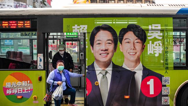 People get off a bus with advertisement of Lai Ching-te, Taiwanese presidential candidate from the ruling Democratic Progressive Party.