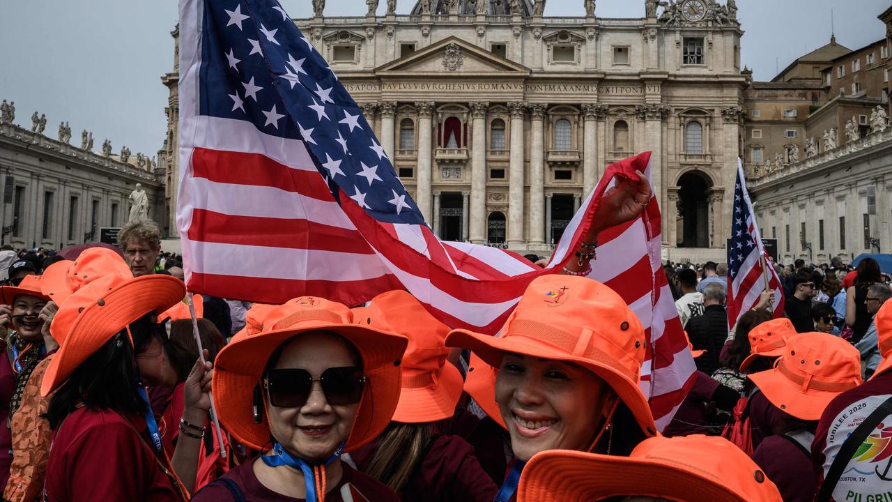 People gather with US flags at St Peter's square with the St Peter's Basilica in the background on the day Pope Leo XIV leads the Regina Caeli prayer, in the Vatican, on May 11, 2025. (Photo by JEFF PACHOUD / AFP)