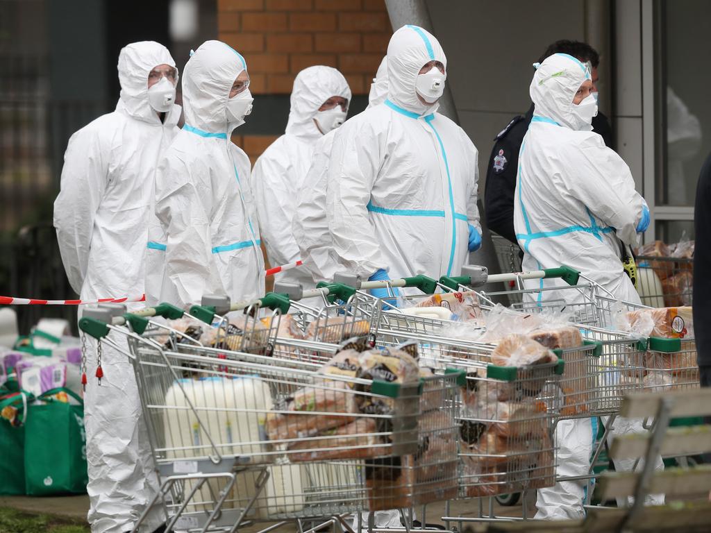 Firefighter in protective suits delivering food to the towers in Melbourne on Tuesday afternoon – days after they were locked down without warning. Picture: David Crosling