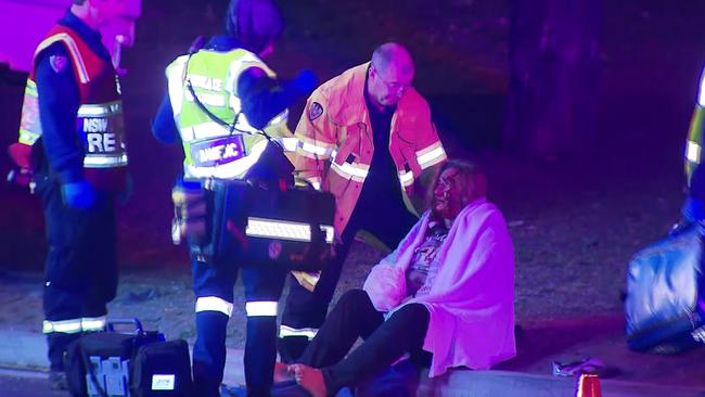 Miracle survivor: A woman is consoled by firefighters and paramedics following a horrific accident. Picture: Oceania productions