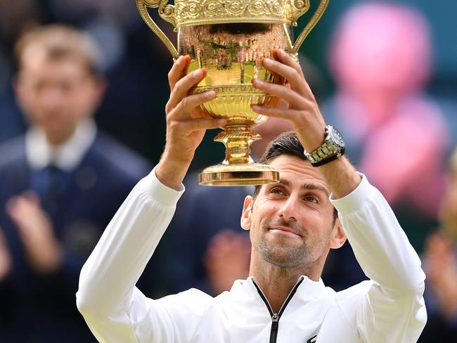 TOPSHOT - Serbia's Novak Djokovic raises the winner's trophy after beating Switzerland's Roger Federer during their men's singles final on day thirteen of the 2019 Wimbledon Championships at The All England Lawn Tennis Club in Wimbledon, southwest London, on July 14, 2019. (Photo by Daniel LEAL-OLIVAS / AFP) / RESTRICTED TO EDITORIAL USE