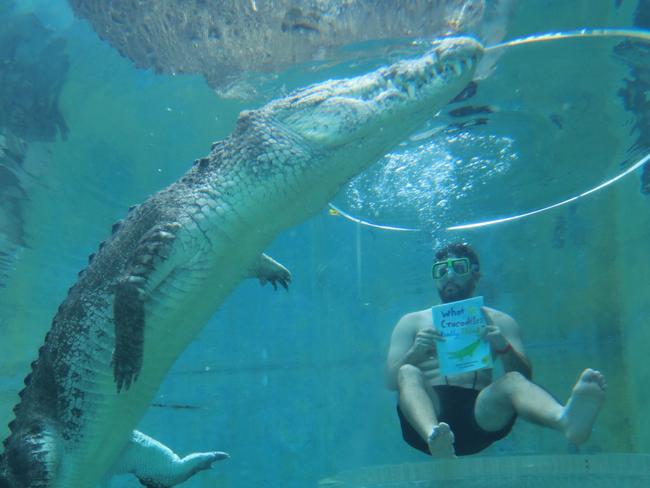 NT librarian PJ Andrews read a local novel inside the Crocosaurus Cove Cage of Death to encourage participation in Australian Reading Hour. Picture: Crocosaurus Cove.